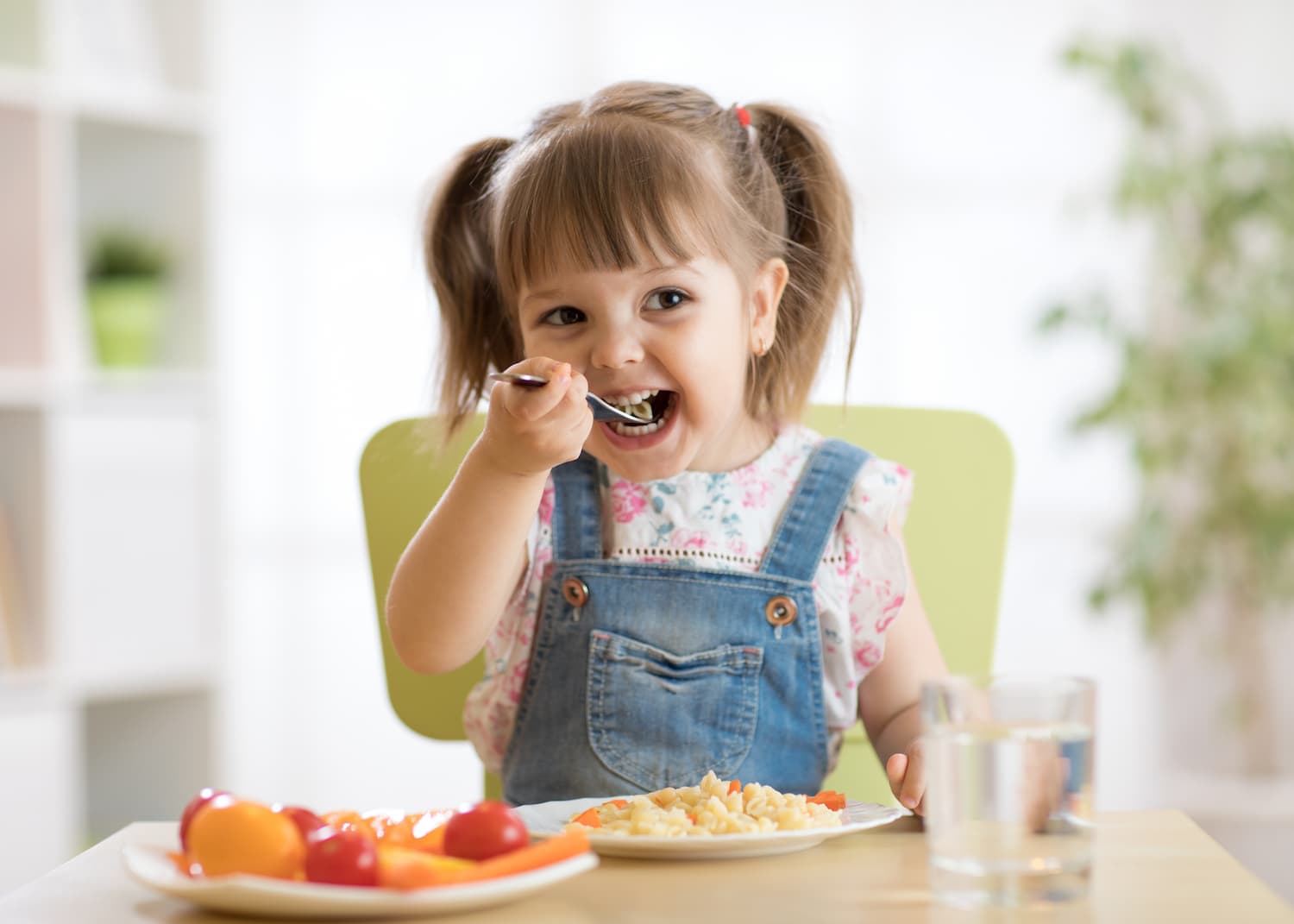 A child smiling whilst eating her dinner