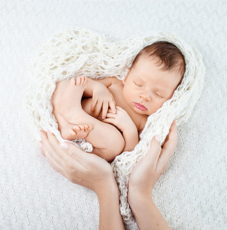 a baby sleeping on a blanket in the shape of a love heart