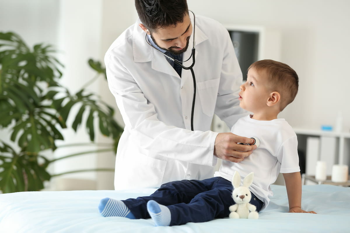 a paediatrician listening to a little boys heart through a stethoscope
