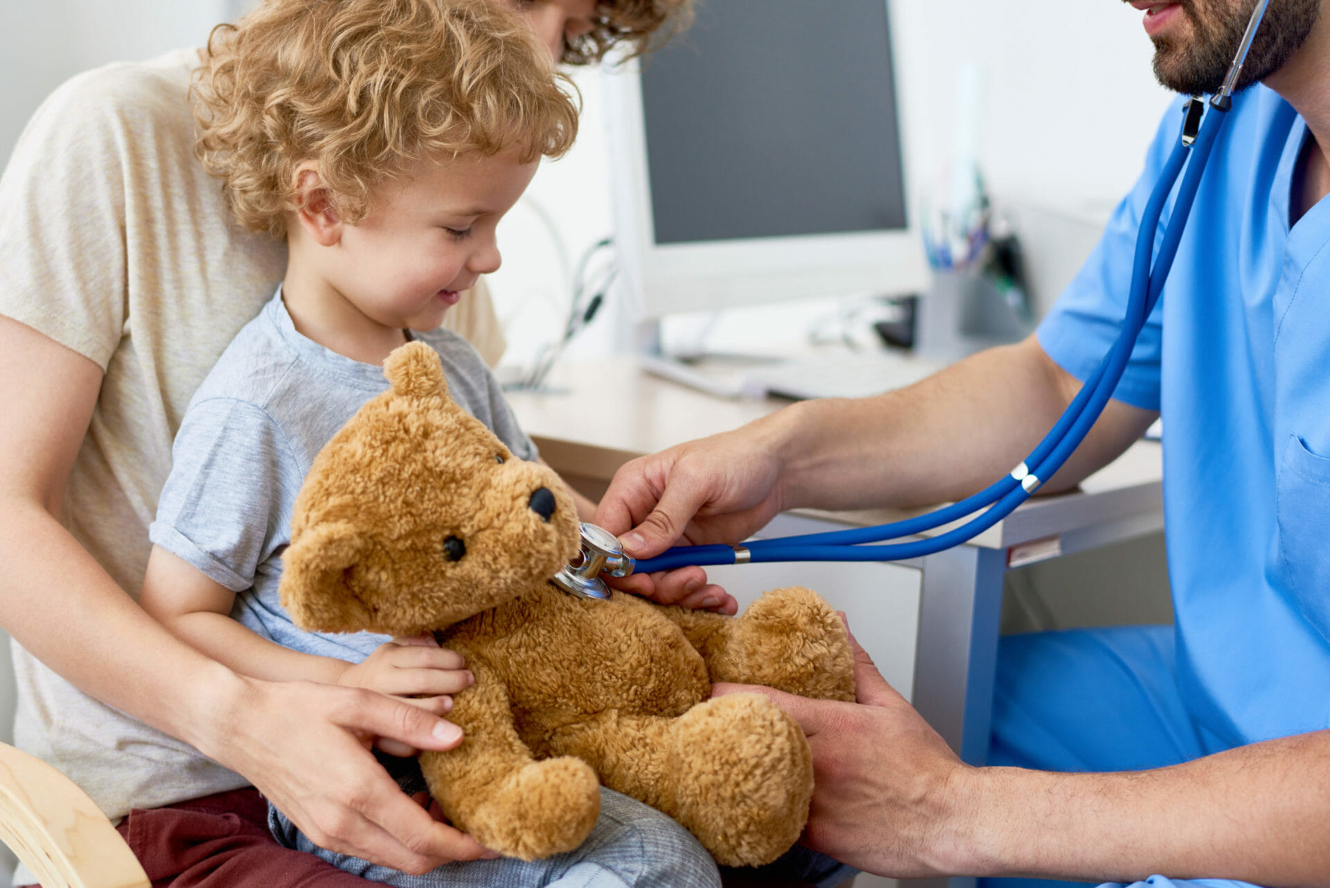 a paediatrician using a stethoscope on a child's stuffed bear