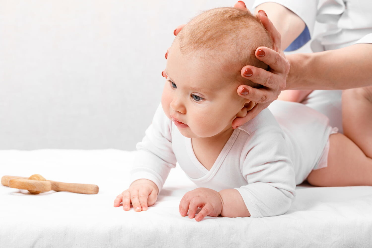A baby crawling whilst a doctor examines its head