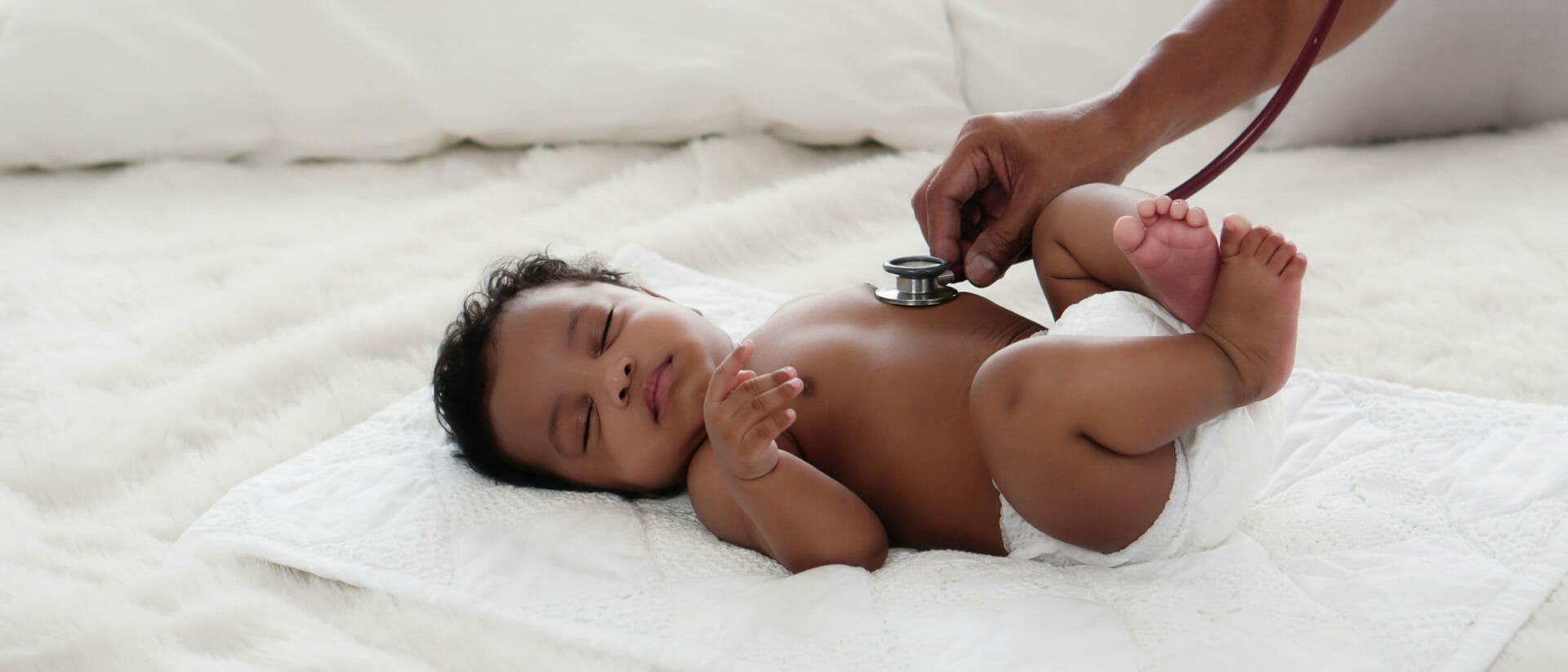 a baby girl lying on her back with a stethoscope pressed onto her chest