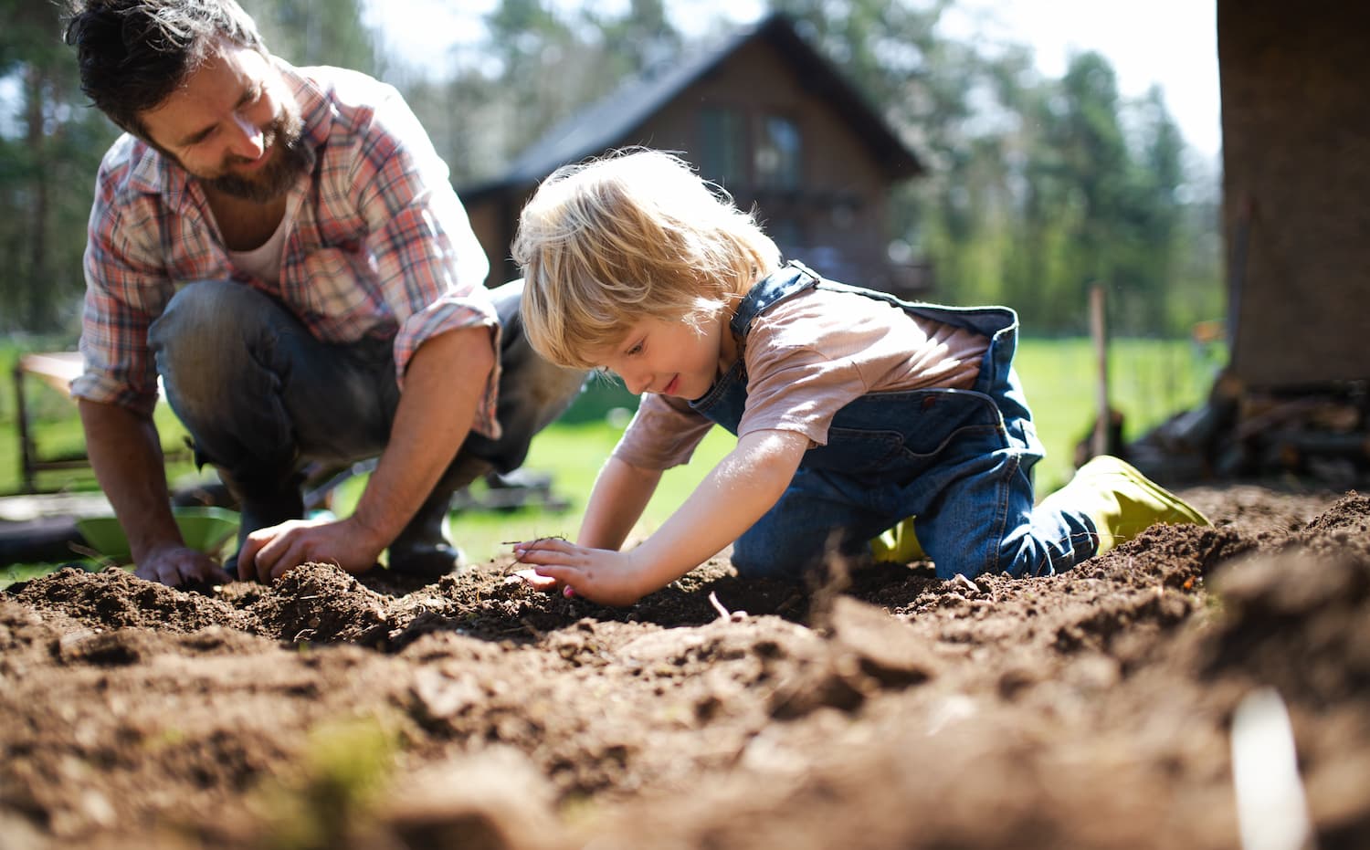 A dad showing his child how to plant a seed in soil