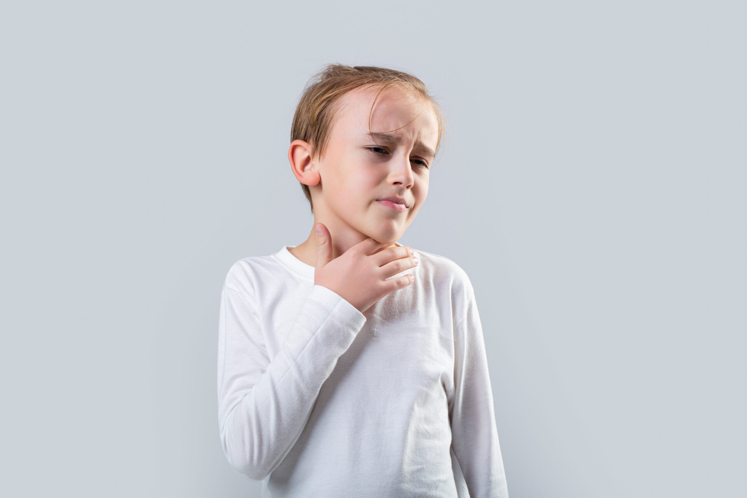 Young boy feels that his throat is pain. Ill little boy with sore throat. Ill child with sore throat. Sore throats in a child. Child has a sore throats. Signs of a cold in children.