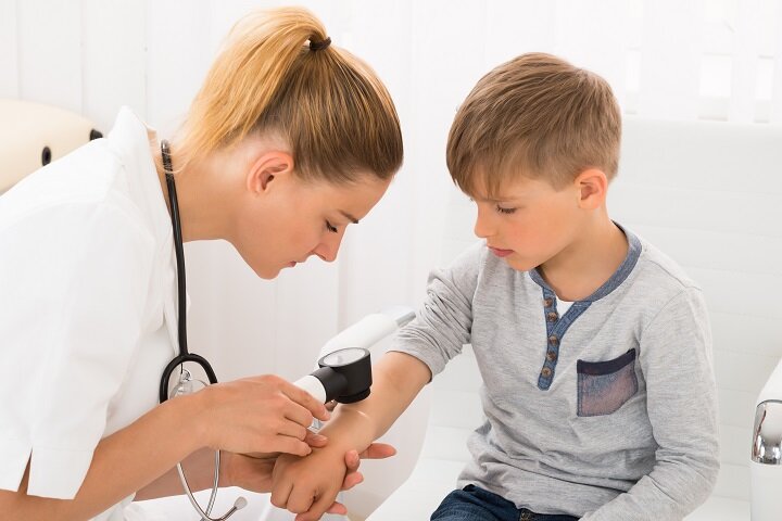 A paediatric doctor examning a child's arm for signs of an allergy.