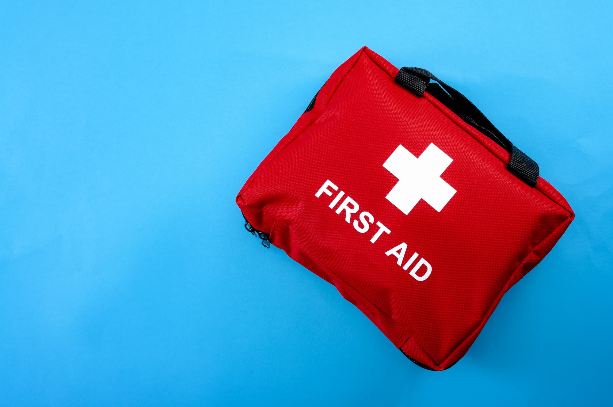 A bright red first aid bag on a blue background