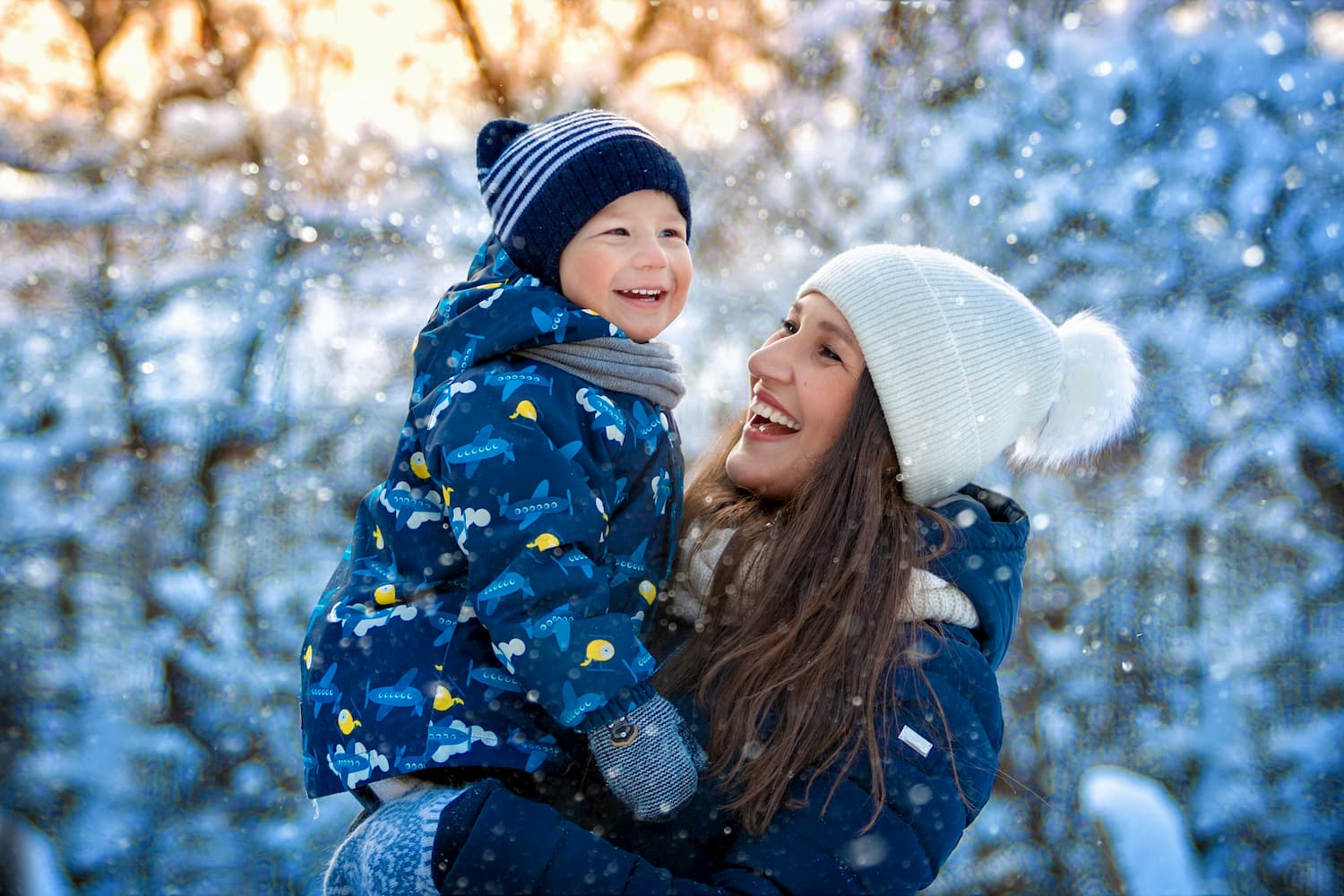A mother smiling and holding her child in the snow
