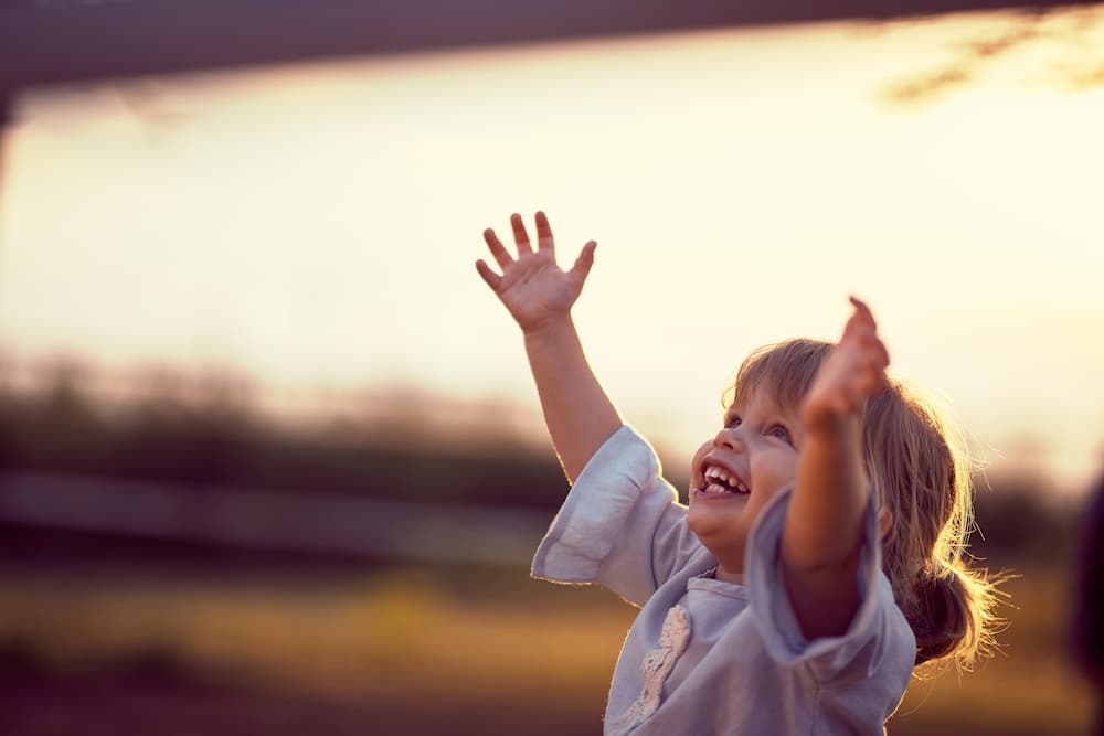 A child holding their arms in the air and smiling